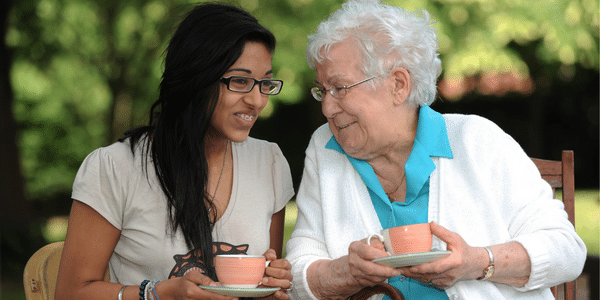 Young woman and older lady drinking tea and talking 
