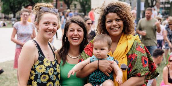 Three smiling women and a baby at community event