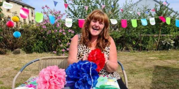 Smiling woman crafting with paper outside with bunting and pompoms