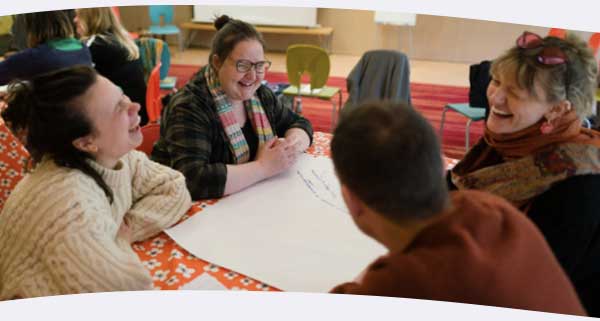 Community members around a table at an event laughing 