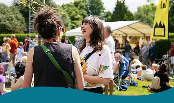 Two women laughing at a community event outside