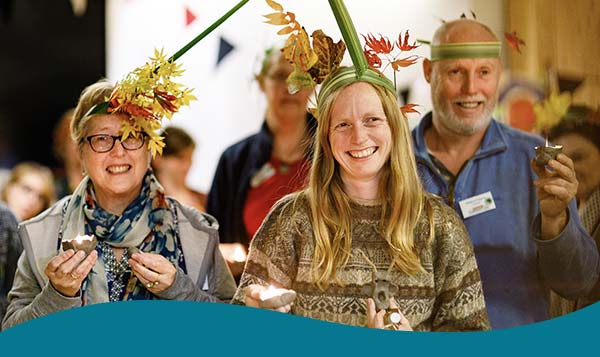 Three people smiling in autumnal headbands at a community event